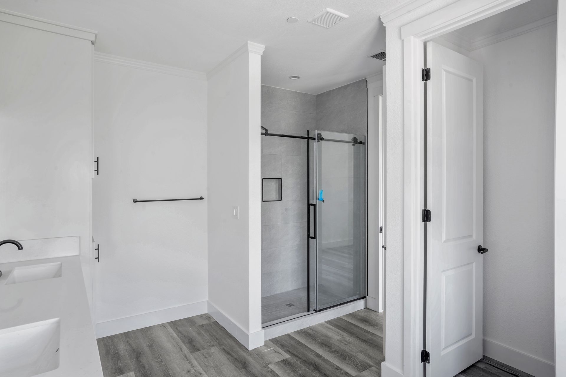 Perpetual Homes ADU: Bathroom with a walk-in shower, white walls, and gray wood-look flooring.
