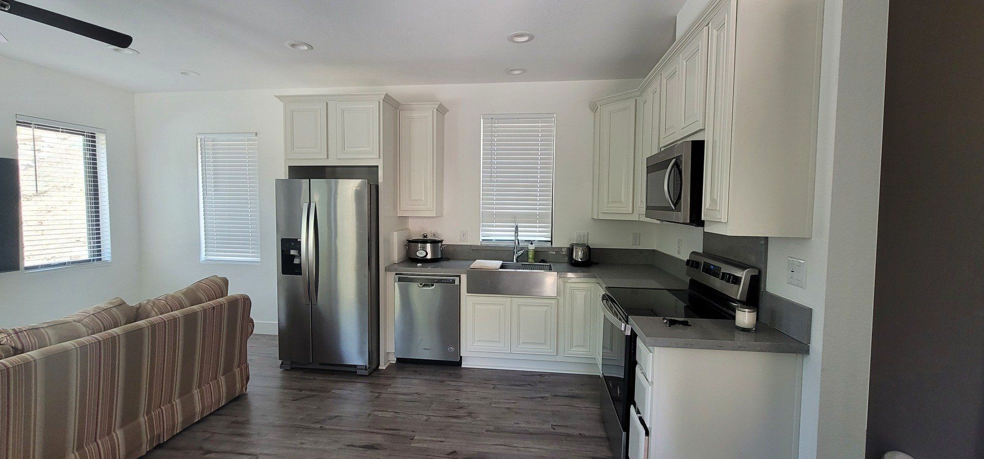 Perpetual Homes ADU: A kitchen with white cabinets, stainless steel appliances, and gray countertops. 