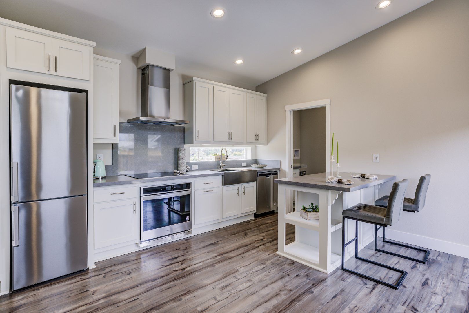 Perpetual Homes ADU: Modern kitchen with white cabinets, stainless steel appliances, island, and wood-look flooring.
