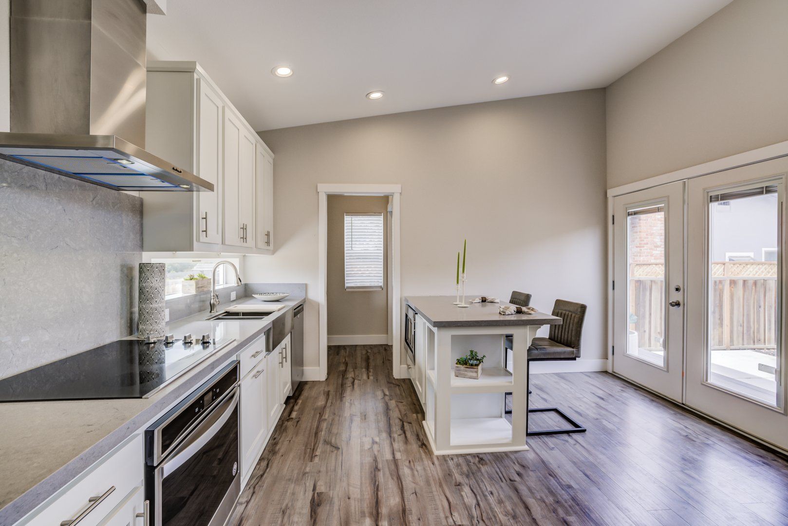 Perpetual Homes ADU: Modern kitchen with white cabinets, stainless steel appliances, and island with seating.