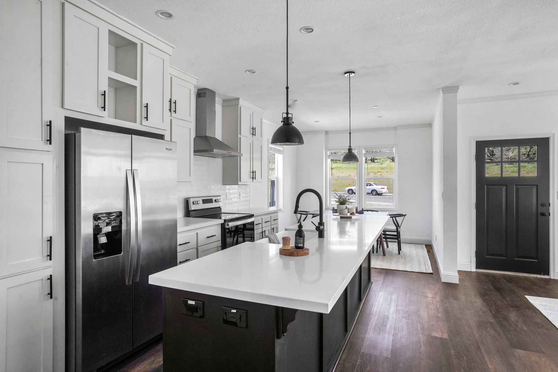 Perpetual Homes ADU: Modern white kitchen with stainless steel appliances, dark island, and black accents.
