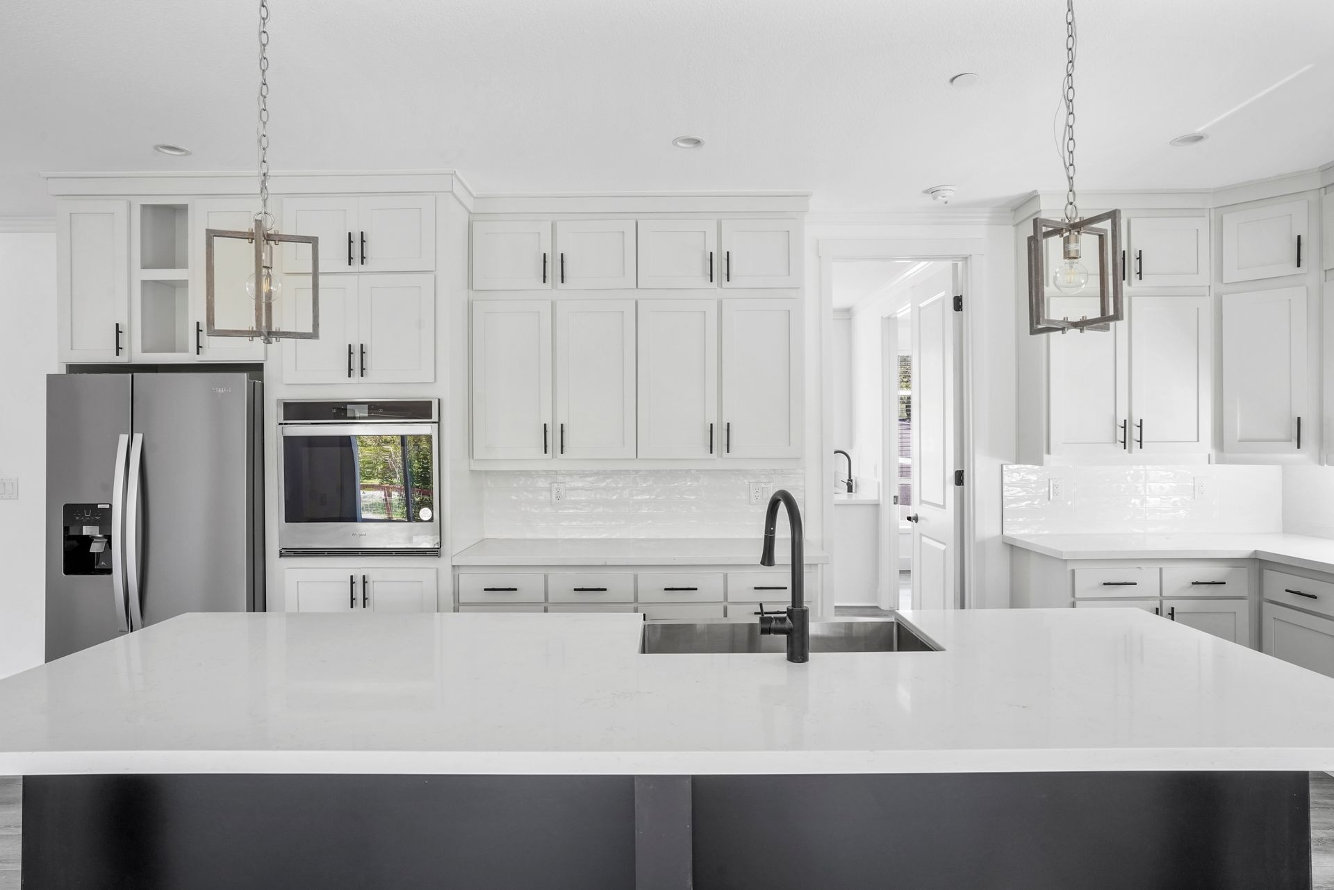 Perpetual Homes ADU: Modern white kitchen with island, stainless steel appliances, and dark sink.