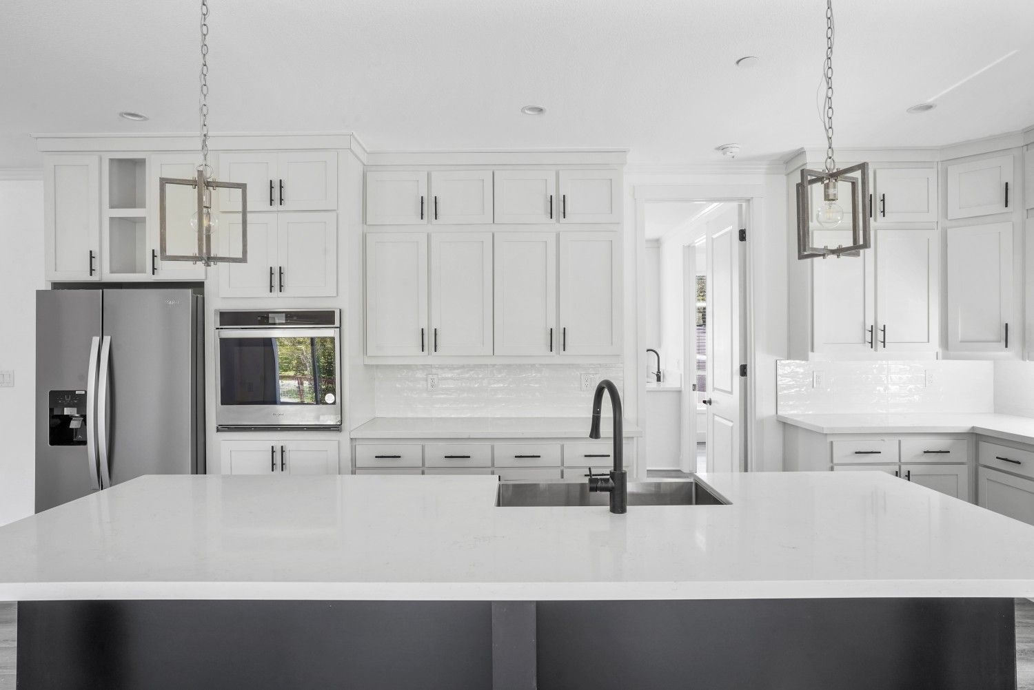 Perpetual Homes ADU: Bright white kitchen with a large island, stainless steel appliances, and dark faucet.