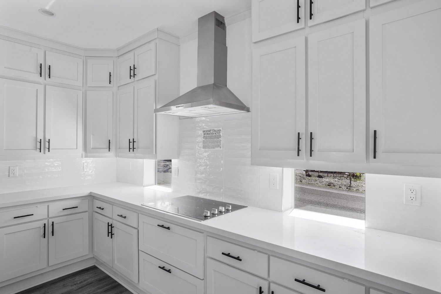 Perpetual Homes ADU: White kitchen with white cabinets, countertops, and backsplash; stainless steel range hood.