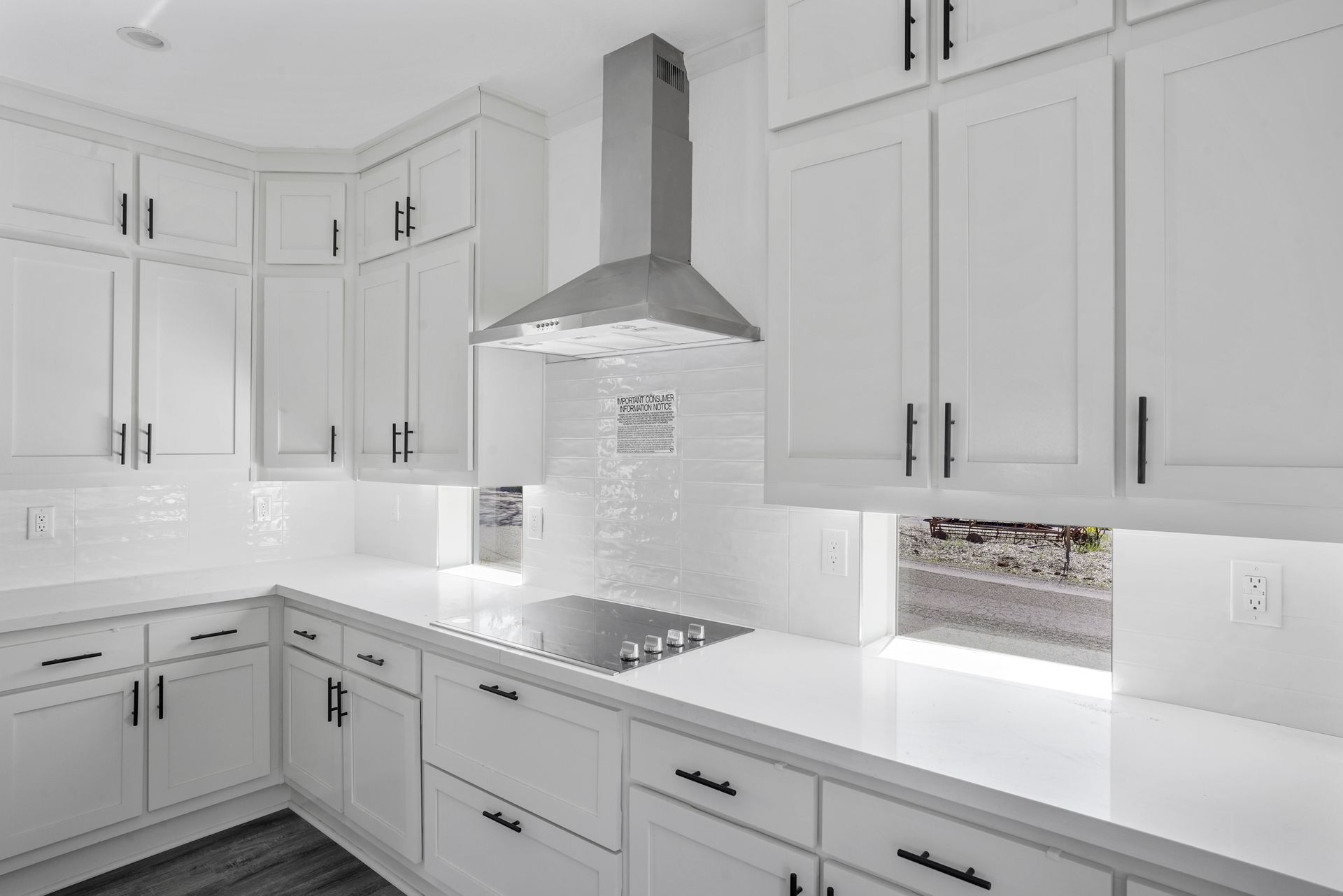 Perpetual Homes ADU: White kitchen with white cabinets, countertops, and backsplash; stainless steel range hood.