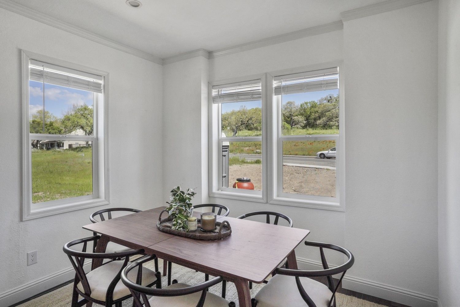 Perpetual Homes ADU: Dining room with table and six chairs near three windows overlooking a yard.