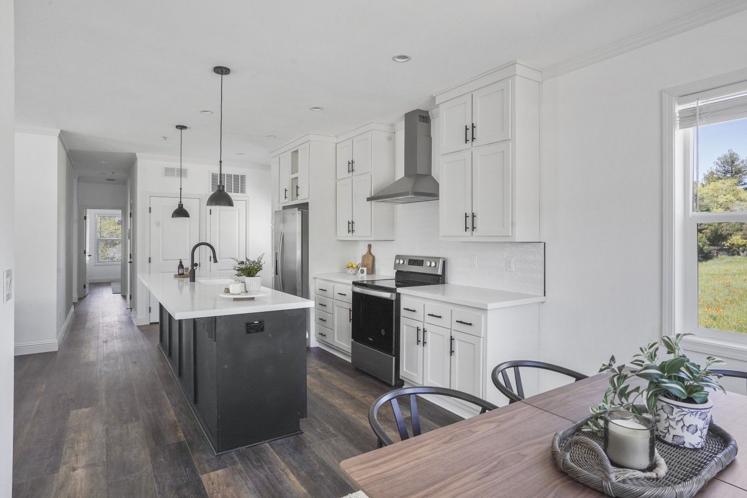 Perpetual Homes ADU: Modern kitchen with white cabinets, dark island, stainless steel appliances, and wood flooring.