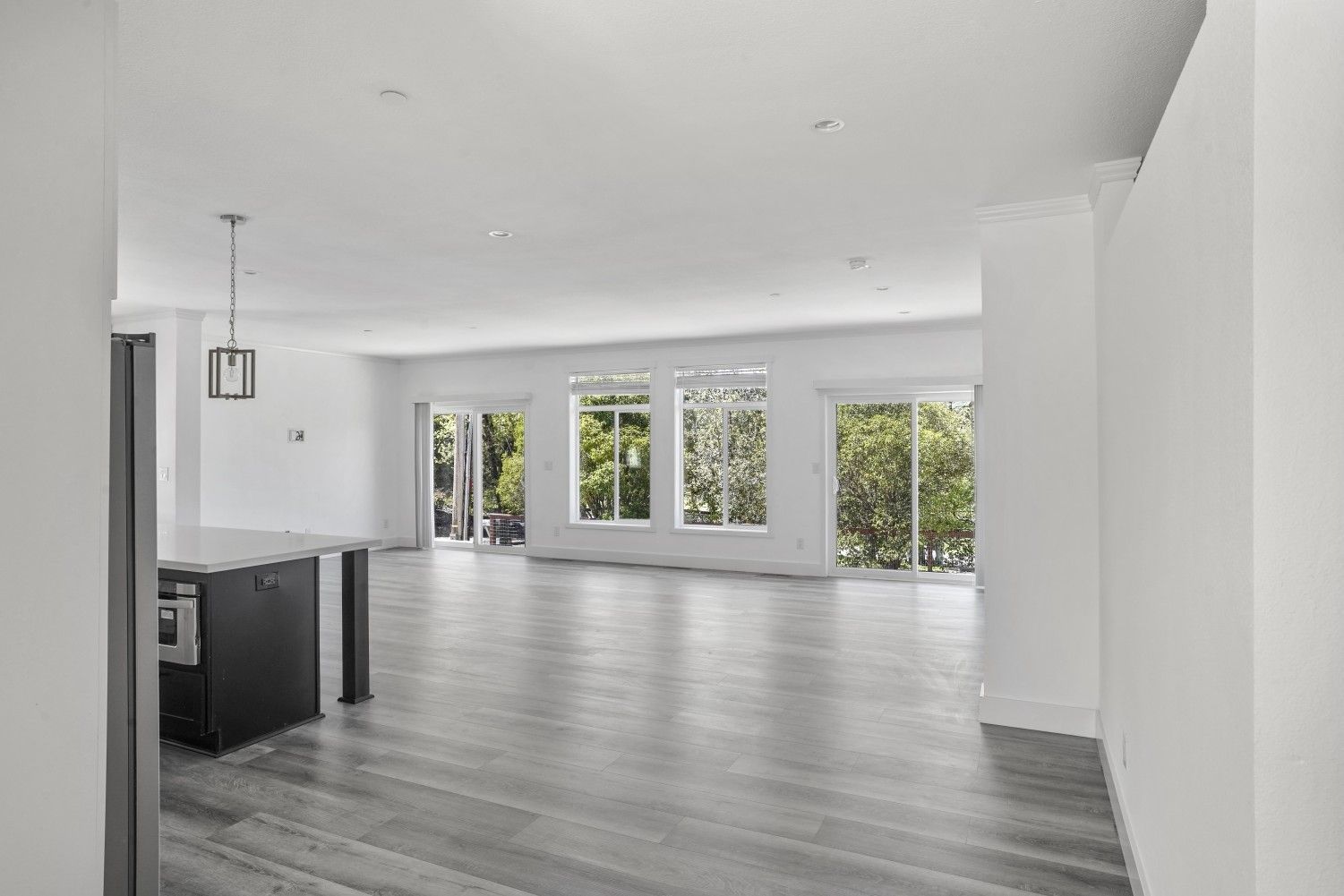 Perpetual Homes ADU: Empty modern living space with gray floors, white walls, and large windows.