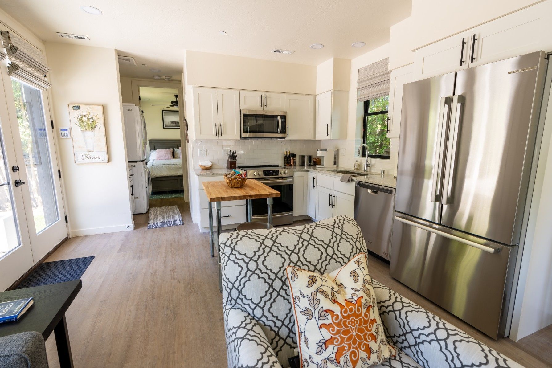 Perpetual Homes ADU: Bright kitchen with white cabinets, stainless steel appliances, and a small wooden island.