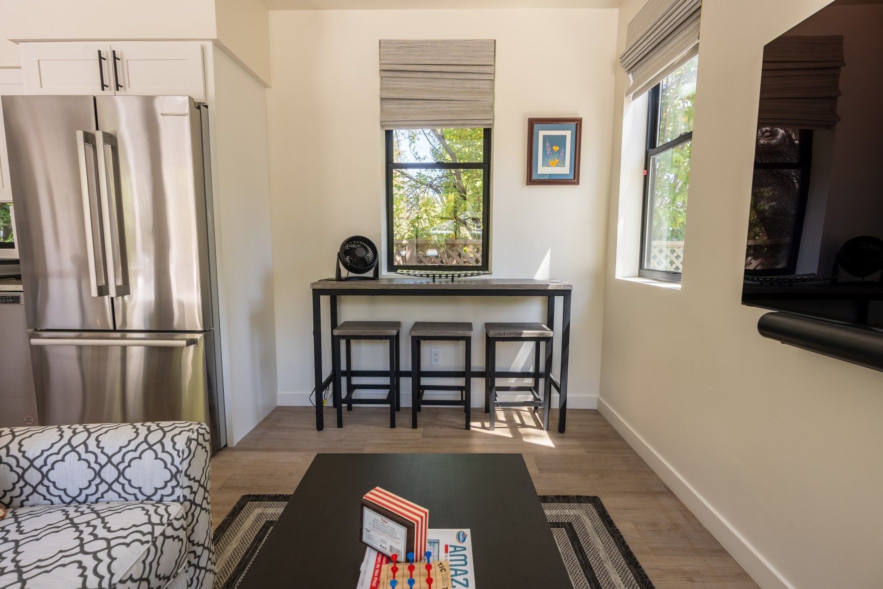 Perpetual Homes ADU: Modern kitchen and dining area with stainless steel fridge, bar, and small rug.