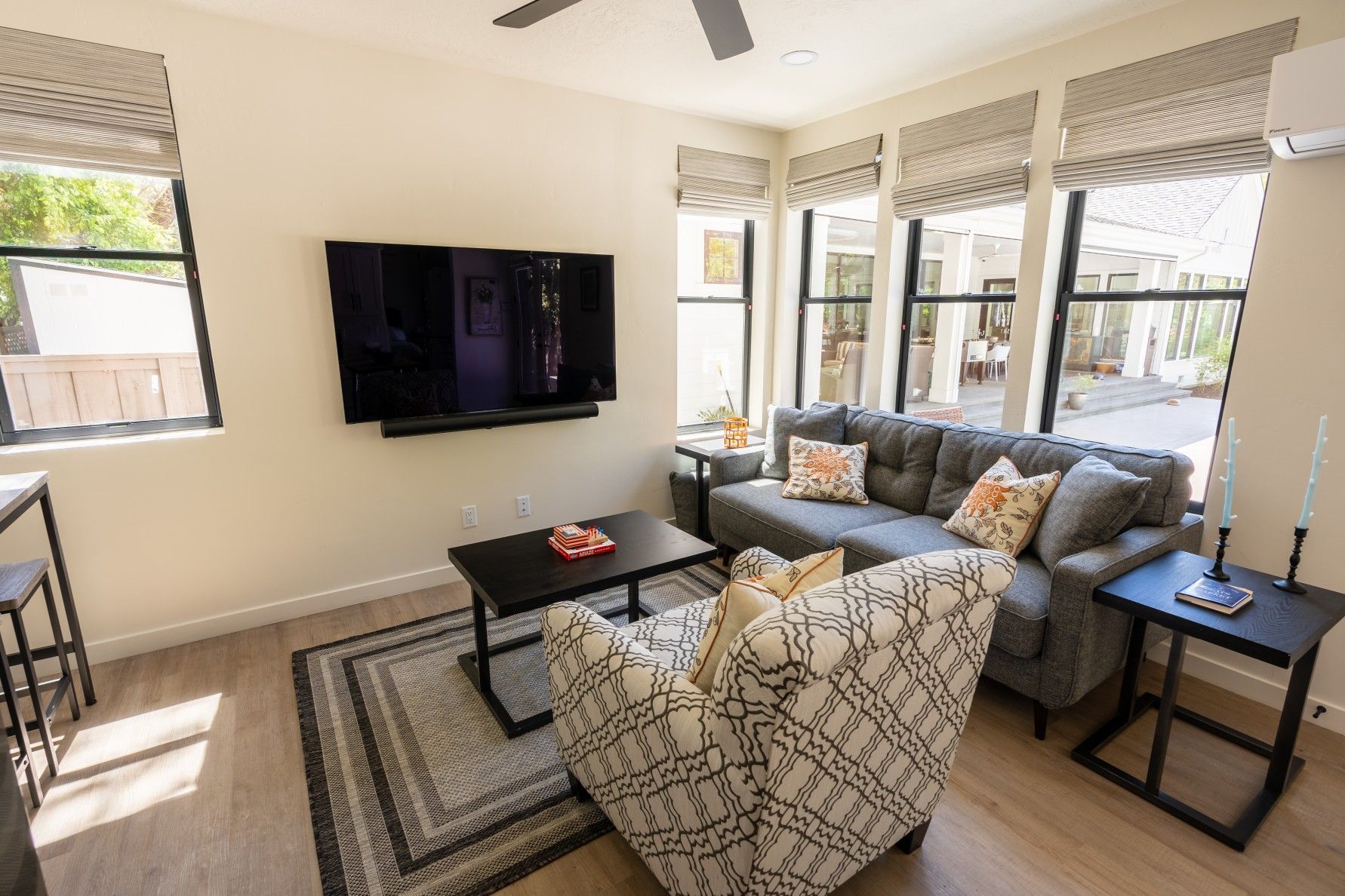 Perpetual Homes ADU: Living room with a gray sofa, a patterned armchair, and a TV mounted on a wall.
