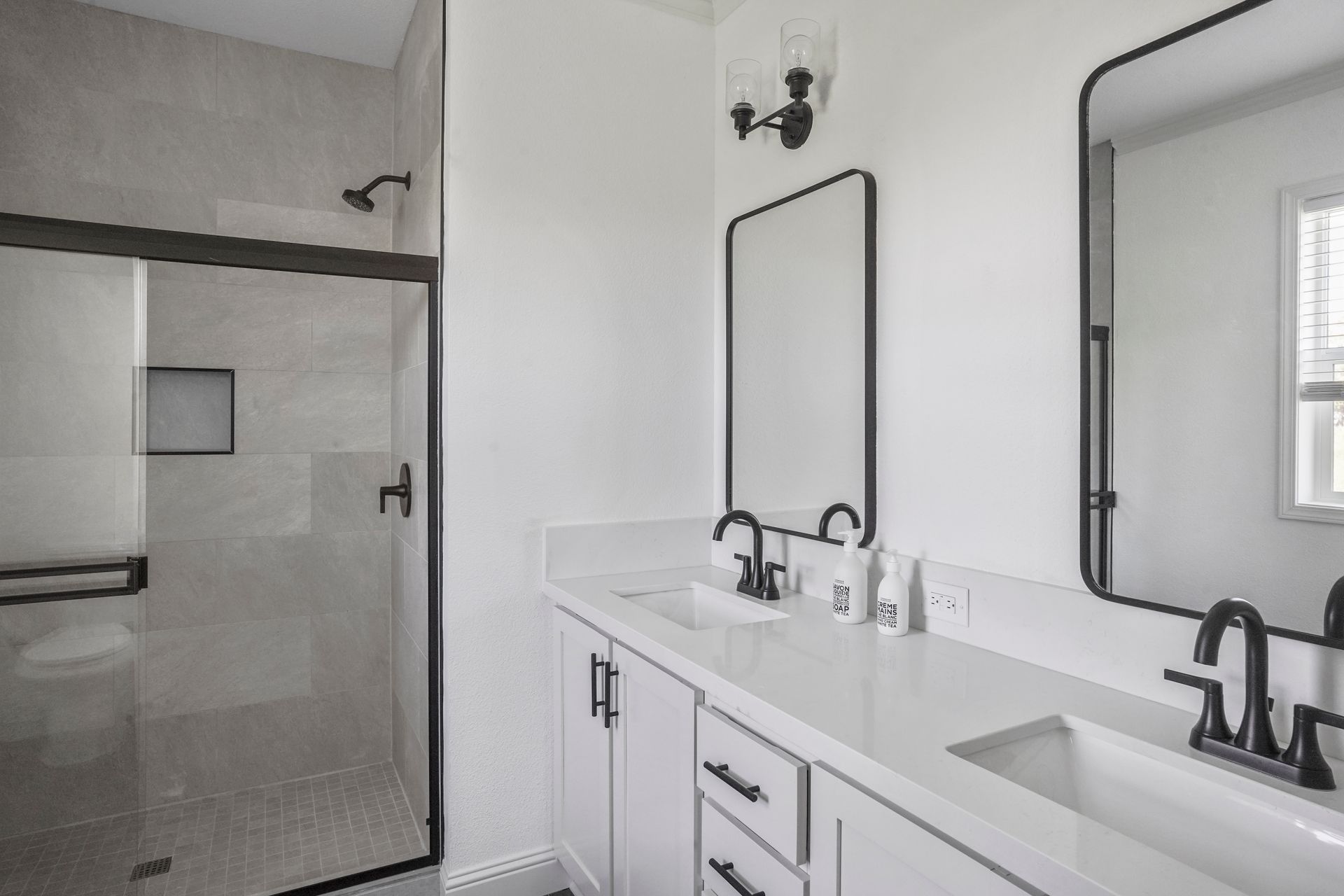Perpetual Homes ADU: Modern white bathroom with shower, double sink vanity, and black accents.