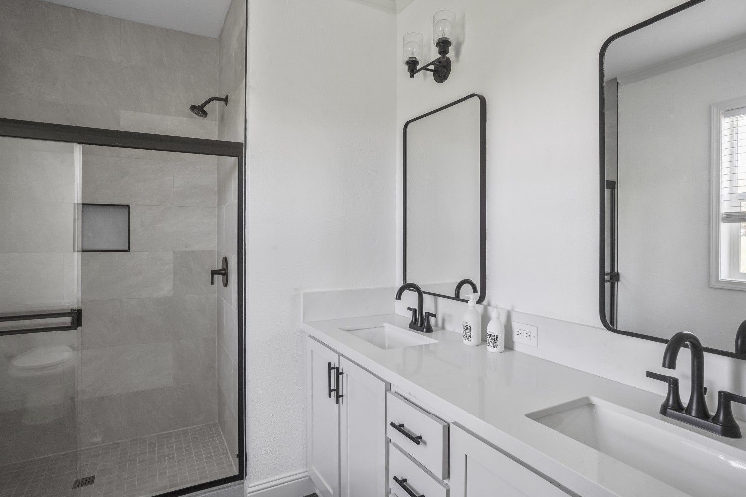 Perpetual Homes ADU: Modern bathroom with white cabinets, quartz countertop, and a glass shower.