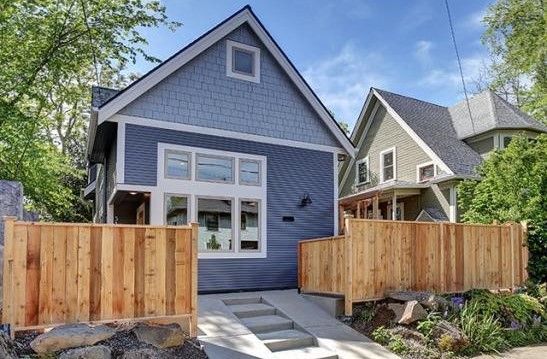 Perpetual Homes ADU: Blue house with wooden fence, gray steps, and a neighboring green house.