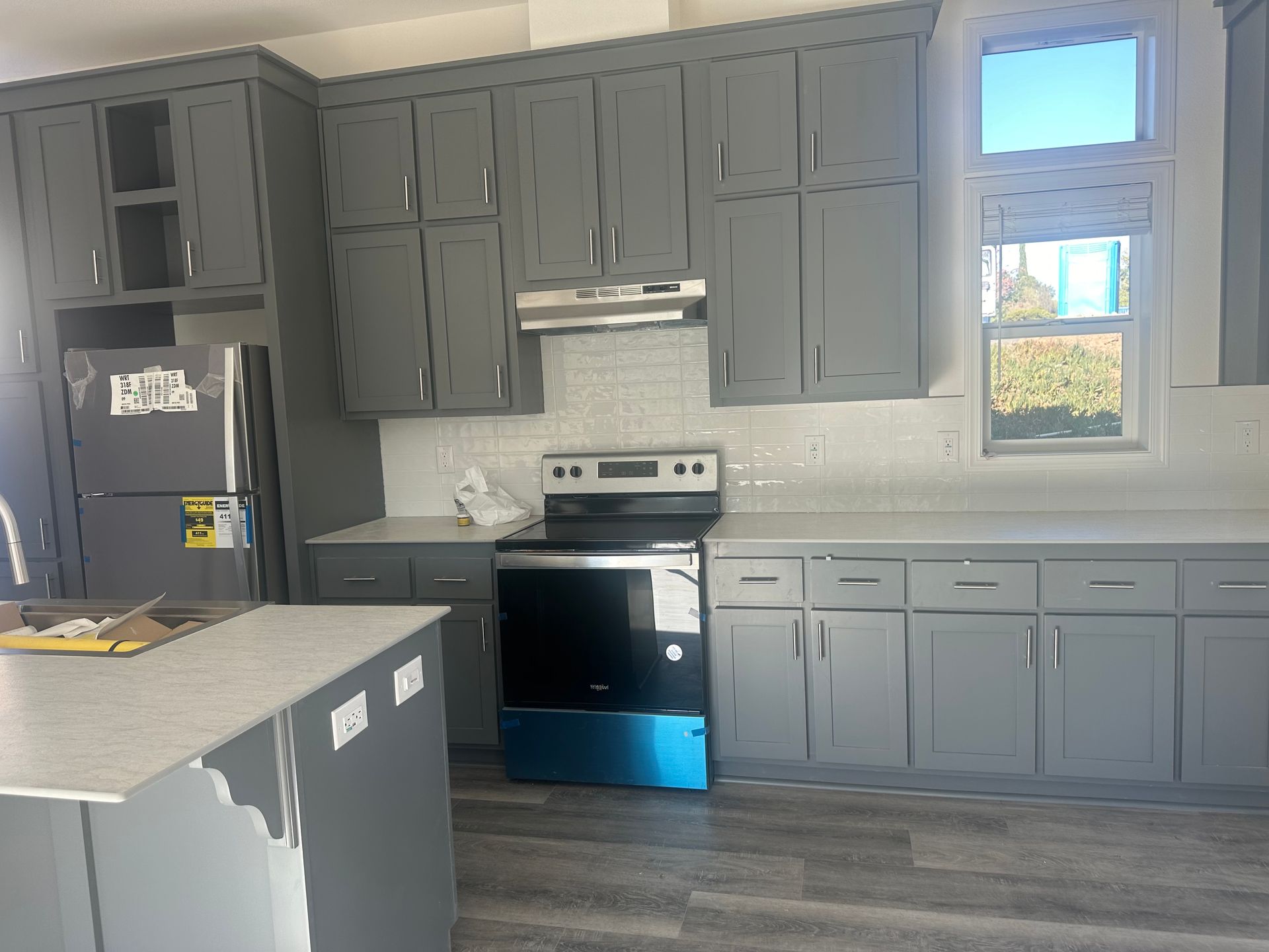 Perpetual Homes ADU: Gray kitchen cabinets with a stainless steel range and white backsplash.