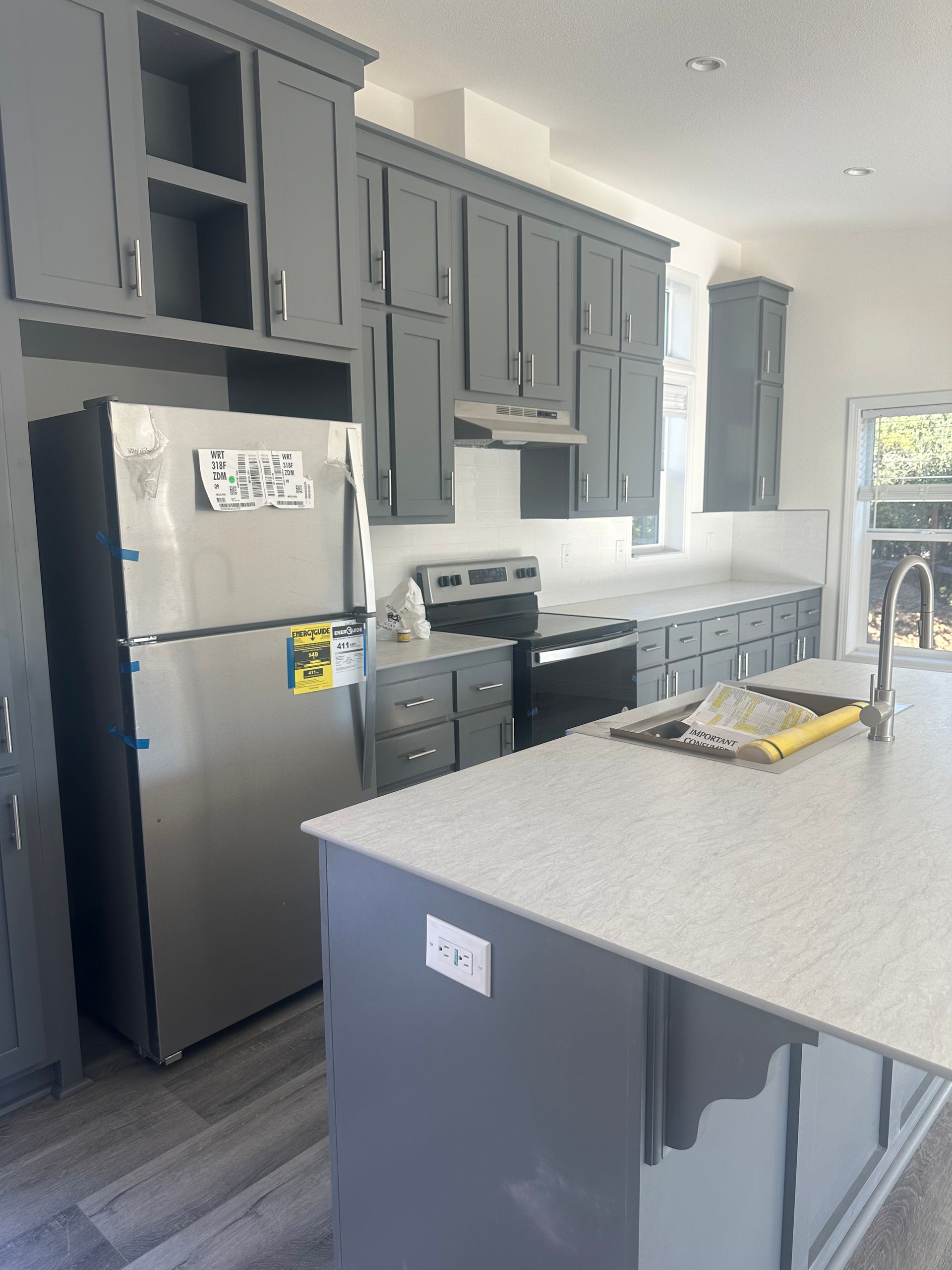 Perpetual Homes ADU: Gray kitchen with cabinets, stainless steel refrigerator, and island with countertop.