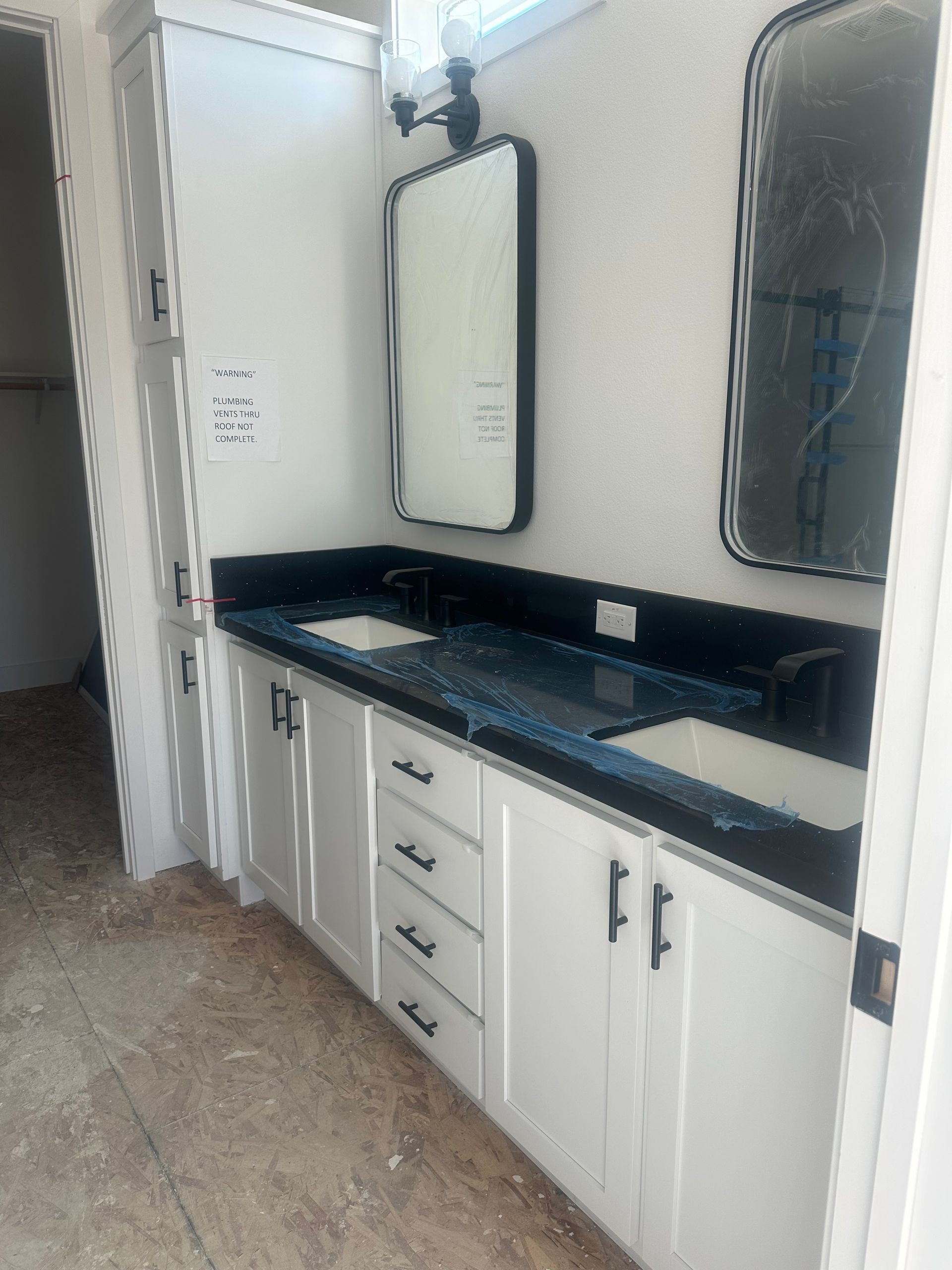 Perpetual Homes ADU: White bathroom vanity with two sinks, black countertops, and two framed mirrors.