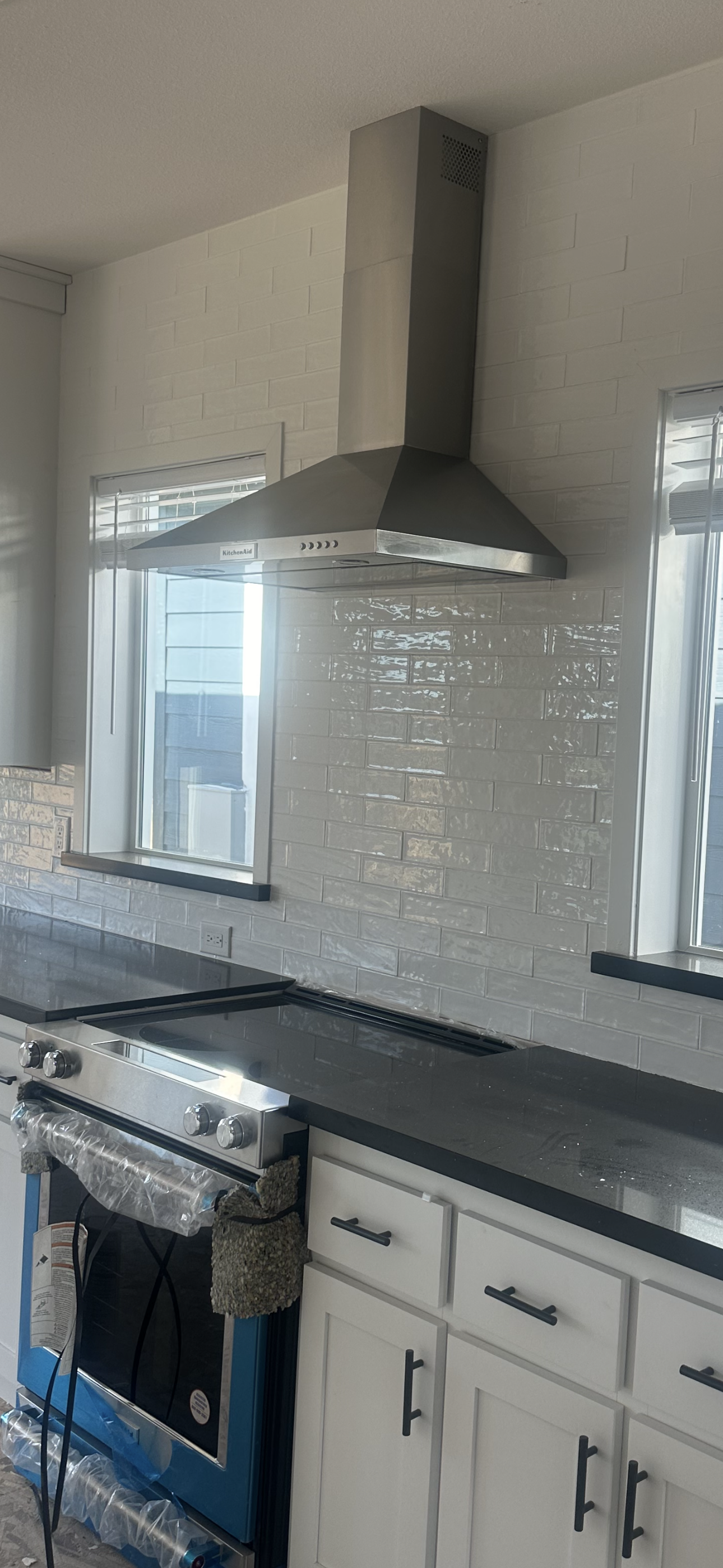 Perpetual Homes ADU: Kitchen with white cabinets, dark countertops, and stainless steel range hood. 
