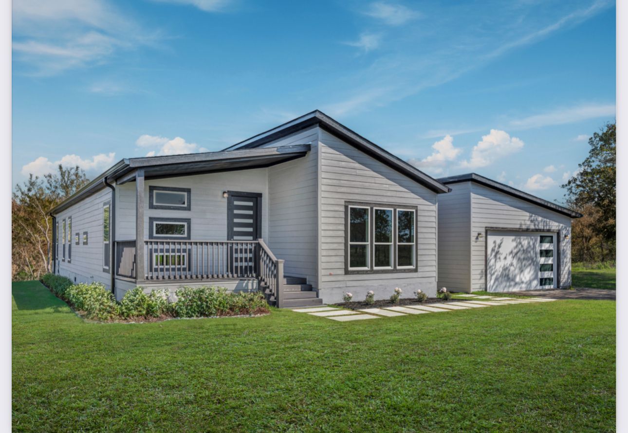 Perpetual Homes ADU: Modern gray house with black accents, porch, and attached garage on green lawn under blue sky.