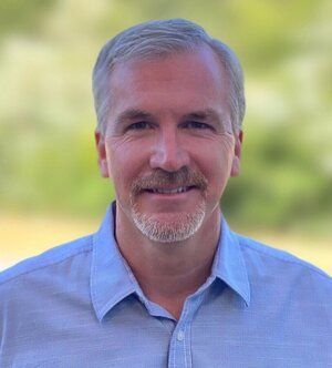 Mark Landolf, Perpetual Homes ADU. Man with graying hair and goatee, wearing light blue button-down shirt. Smiling outdoors.
