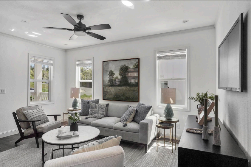 Perpetual Homes ADU: Living room with gray sofa, armchairs, coffee table, art, windows, and TV.