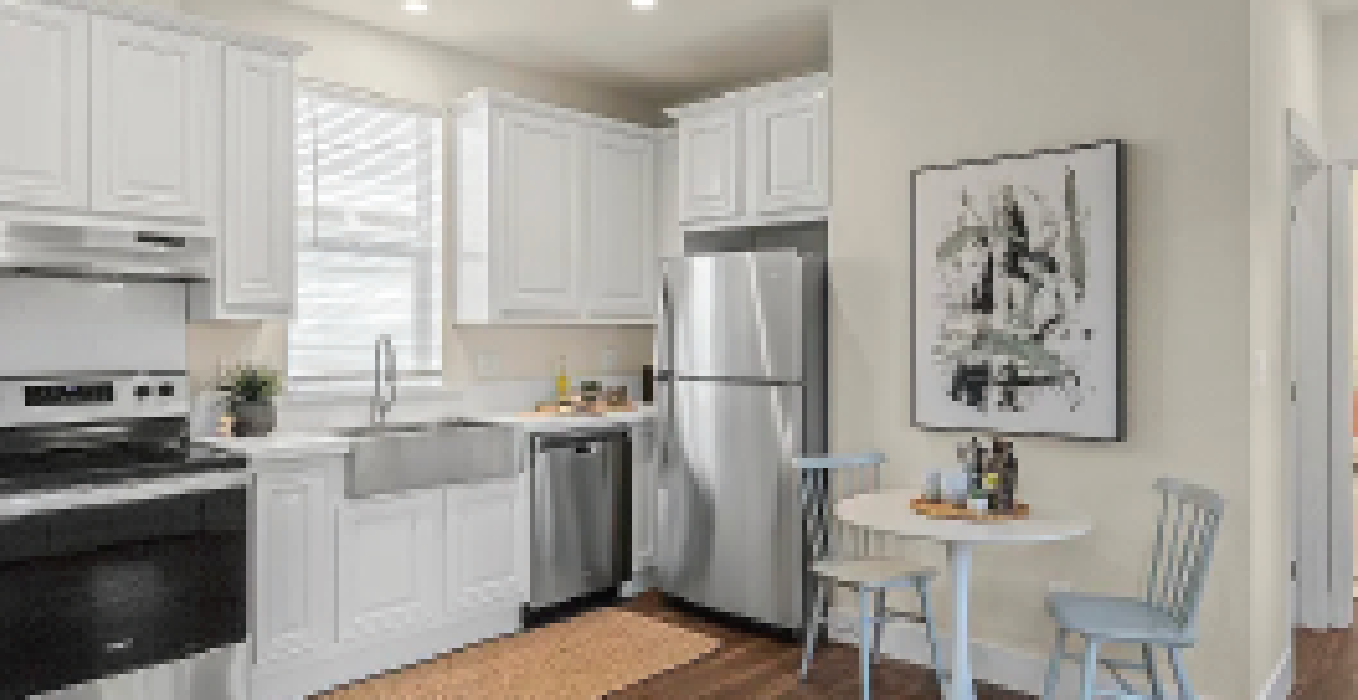 Perpetual Homes ADU: White kitchen with stainless steel appliances, white cabinets, and small dining table.