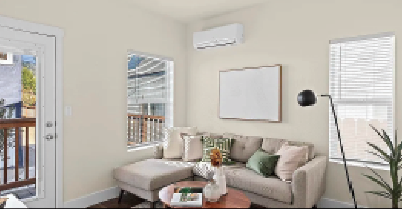 Perpetual Homes ADU: Living room with sectional sofa, windows, and mounted air conditioner.
