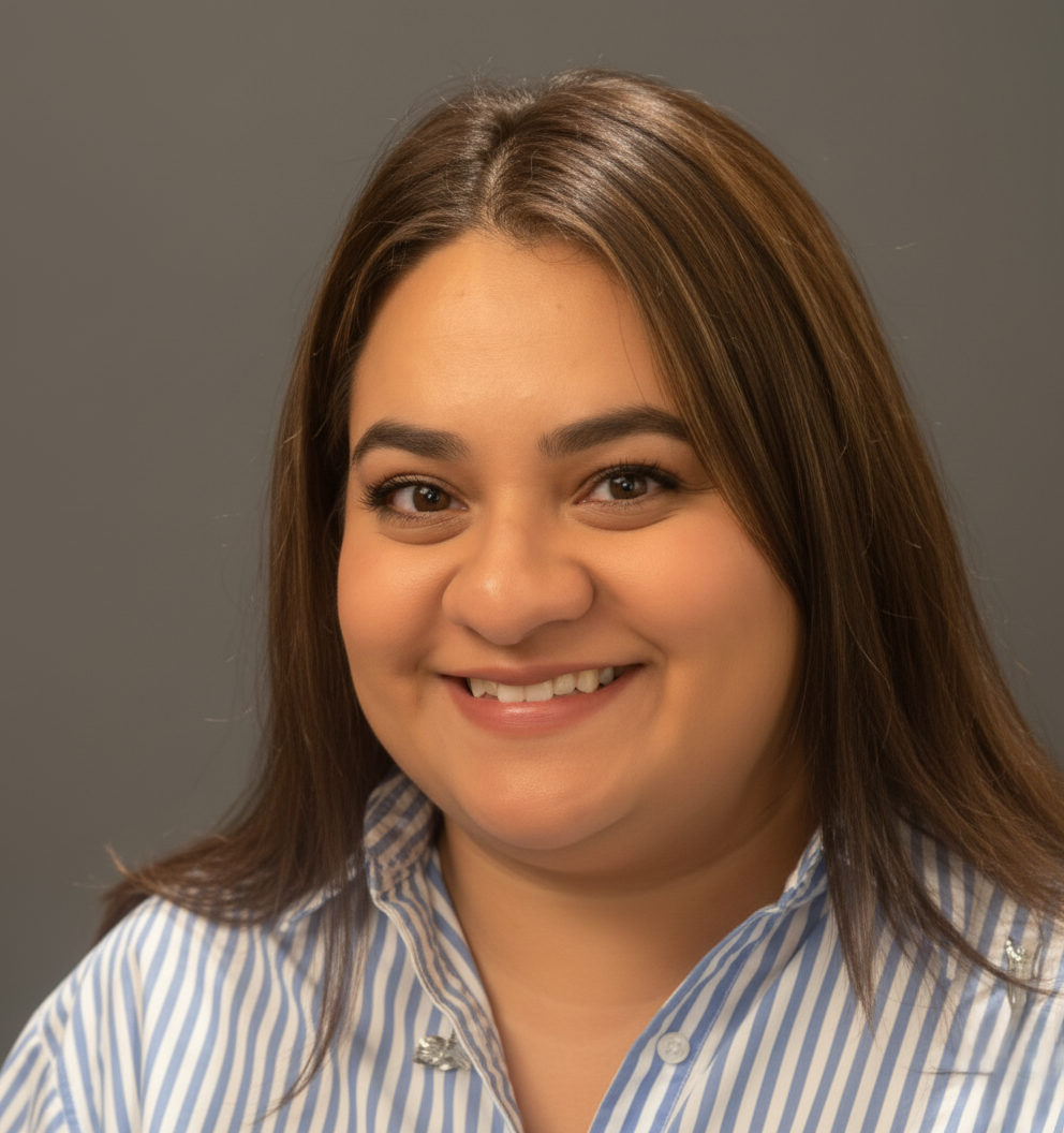 Selena Ramos, Perpetual Homes ADU. Woman smiling, wearing a striped blue and white shirt, against a gray background.