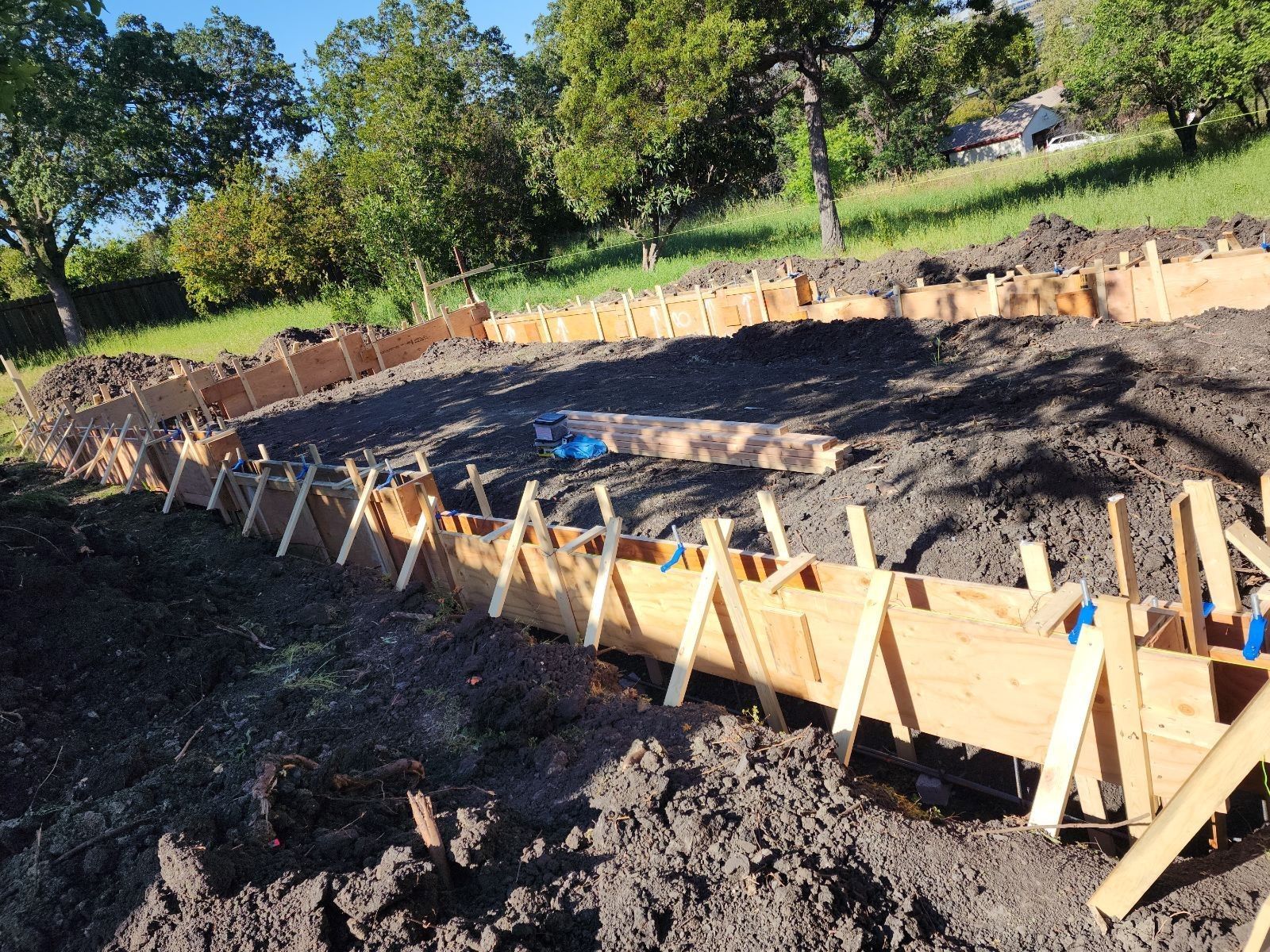 Perpetual Homes ADU: Wooden forms outlining a curved structure on a dirt plot outdoors, likely for a concrete project.