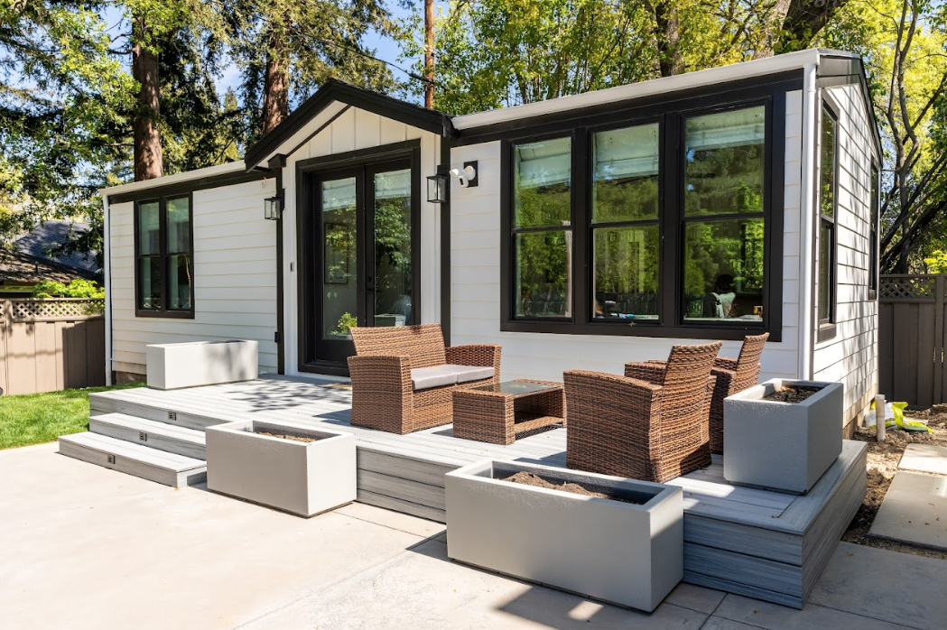 Perpetual Homes ADU: Small white house with a black trim, and outdoor seating on a gray deck.