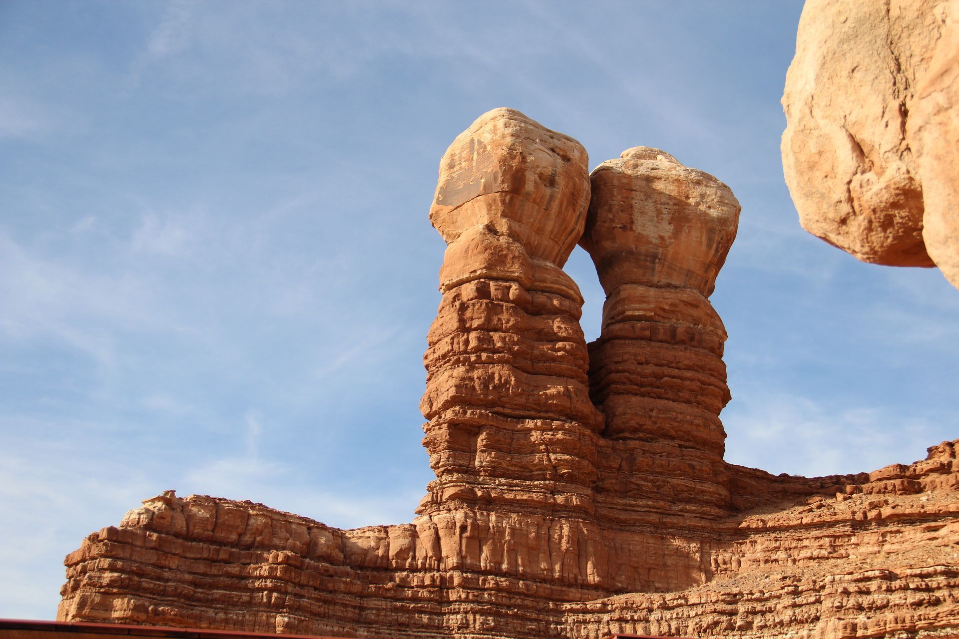 Red sandstone rock formation with two tall pillars beneath a blue sky in a desert landscape