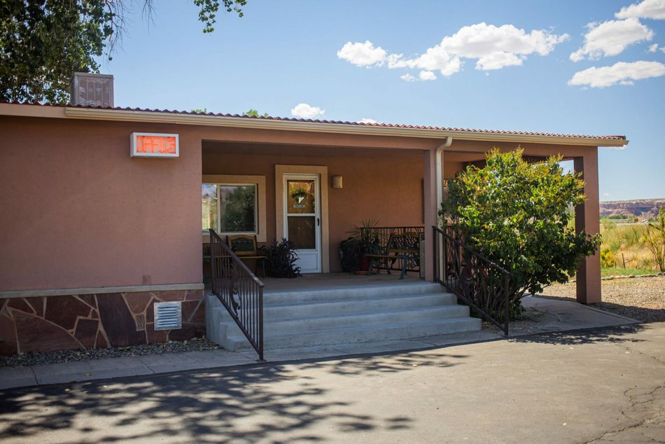 Small tan building with steps, ramp, and a front porch under a blue sky