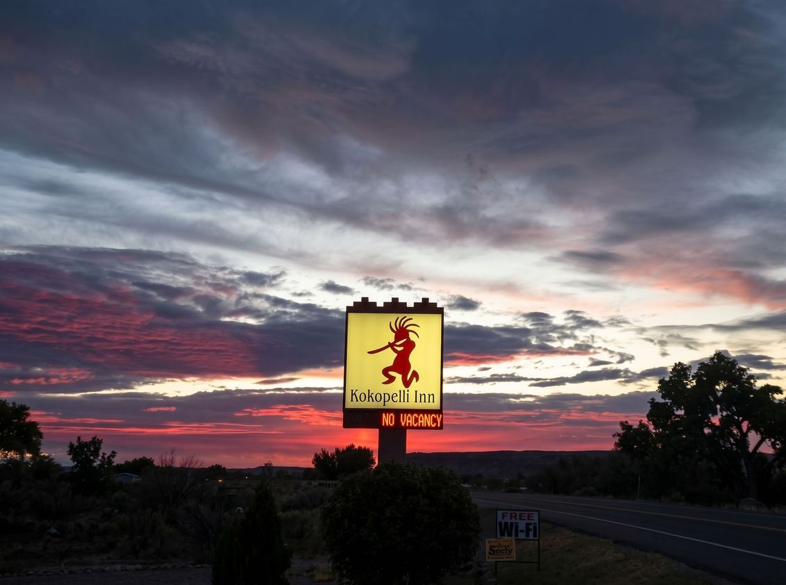 Roadside sign with a red lion logo beside a rural highway under a bright blue sky