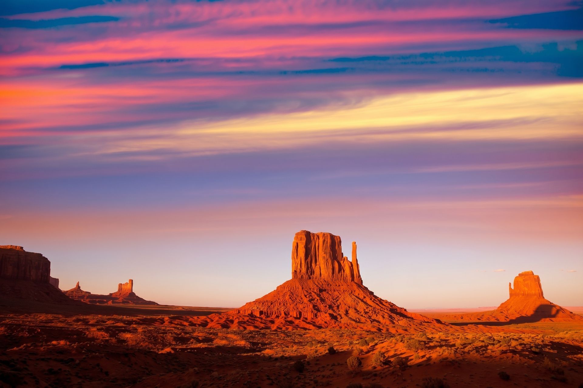 Desert mesas at sunset under a colorful pink and orange sky