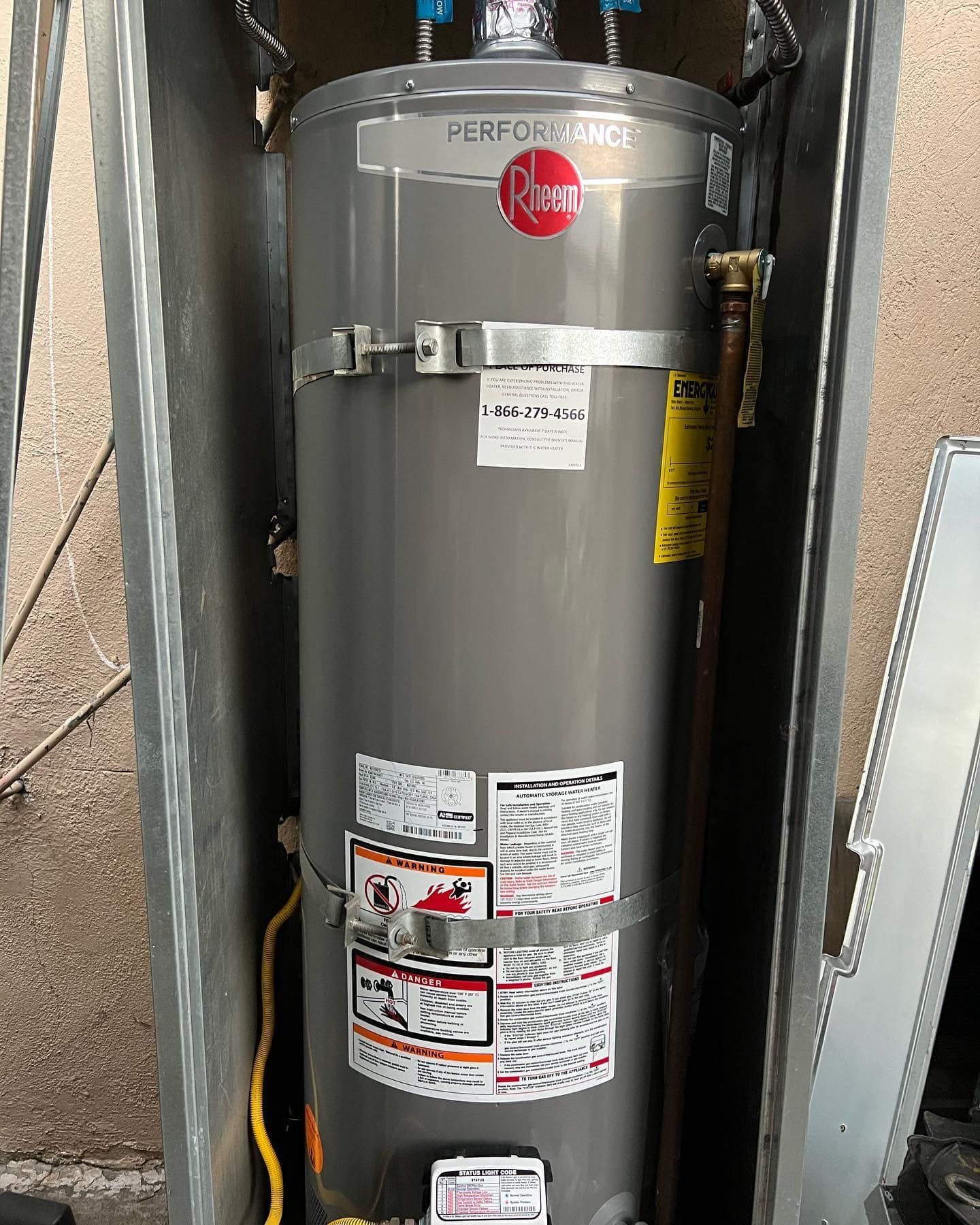 A gray water heater is sitting inside of a metal box.