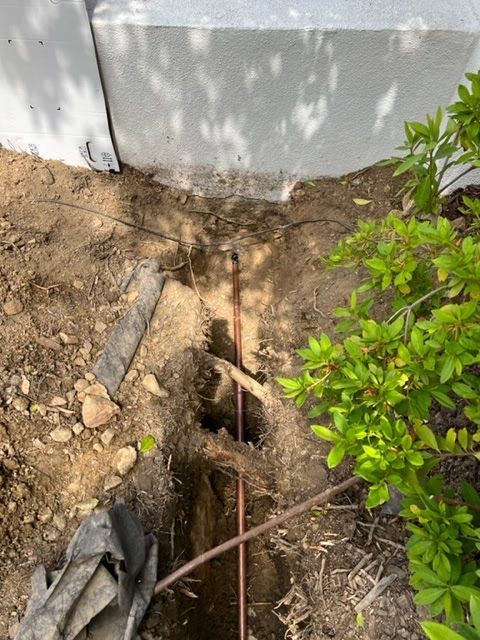 A hole in the ground with a copper wire sticking out of it.