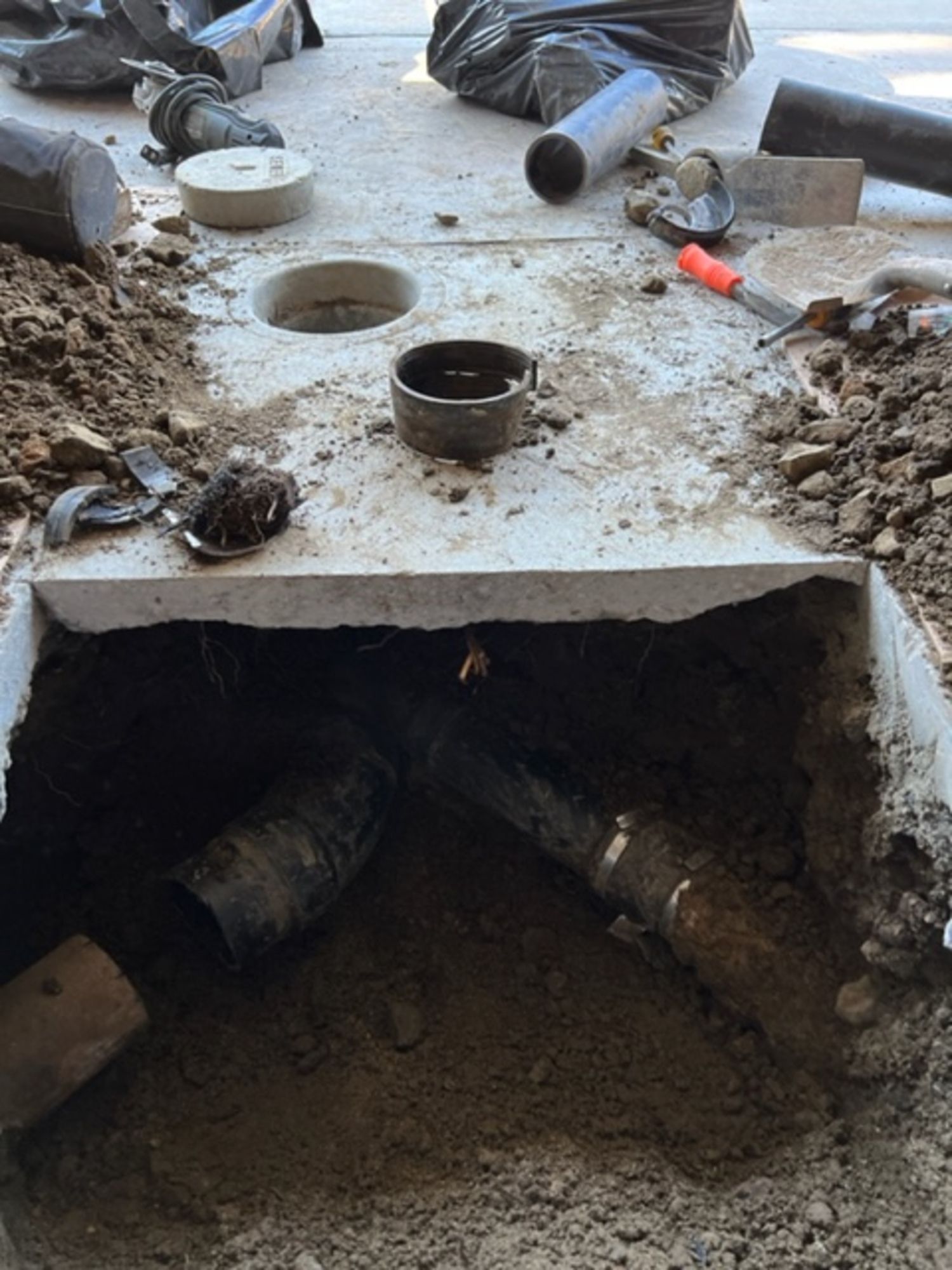 A hole in the ground with pipes coming out of it.