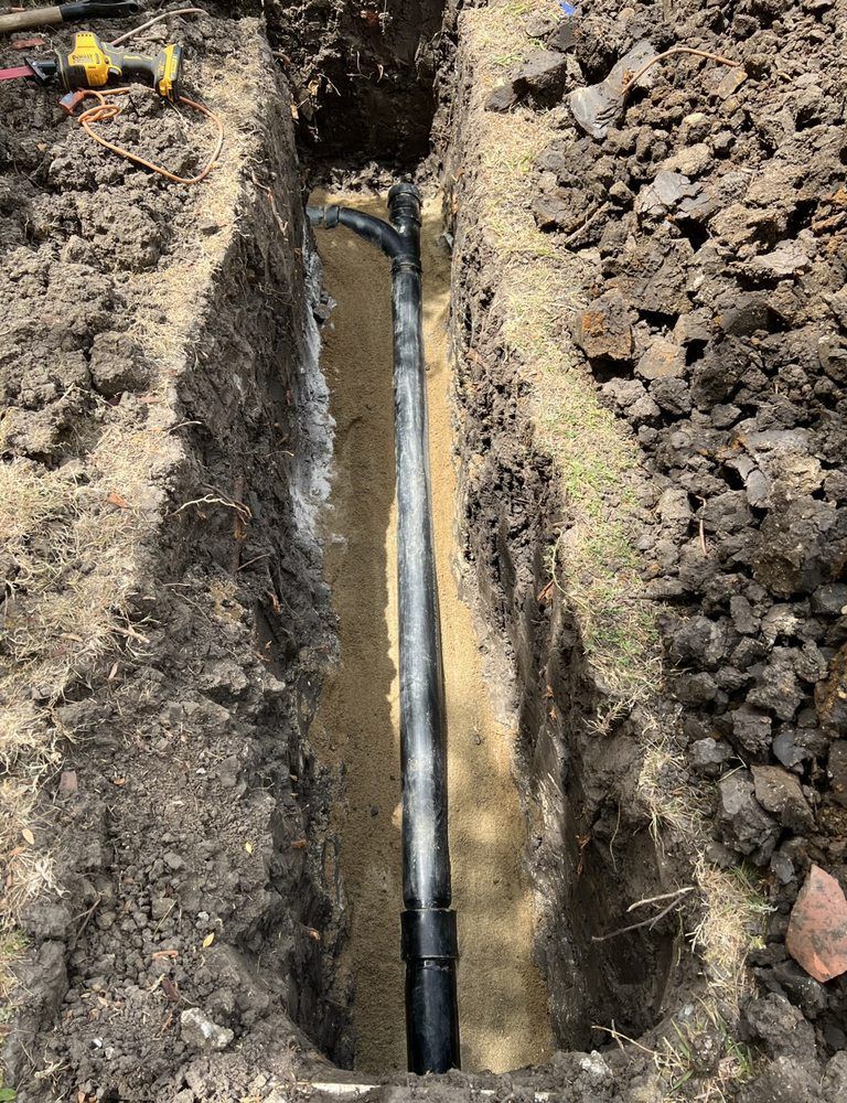 A pipe is being installed in a trench in the dirt.
