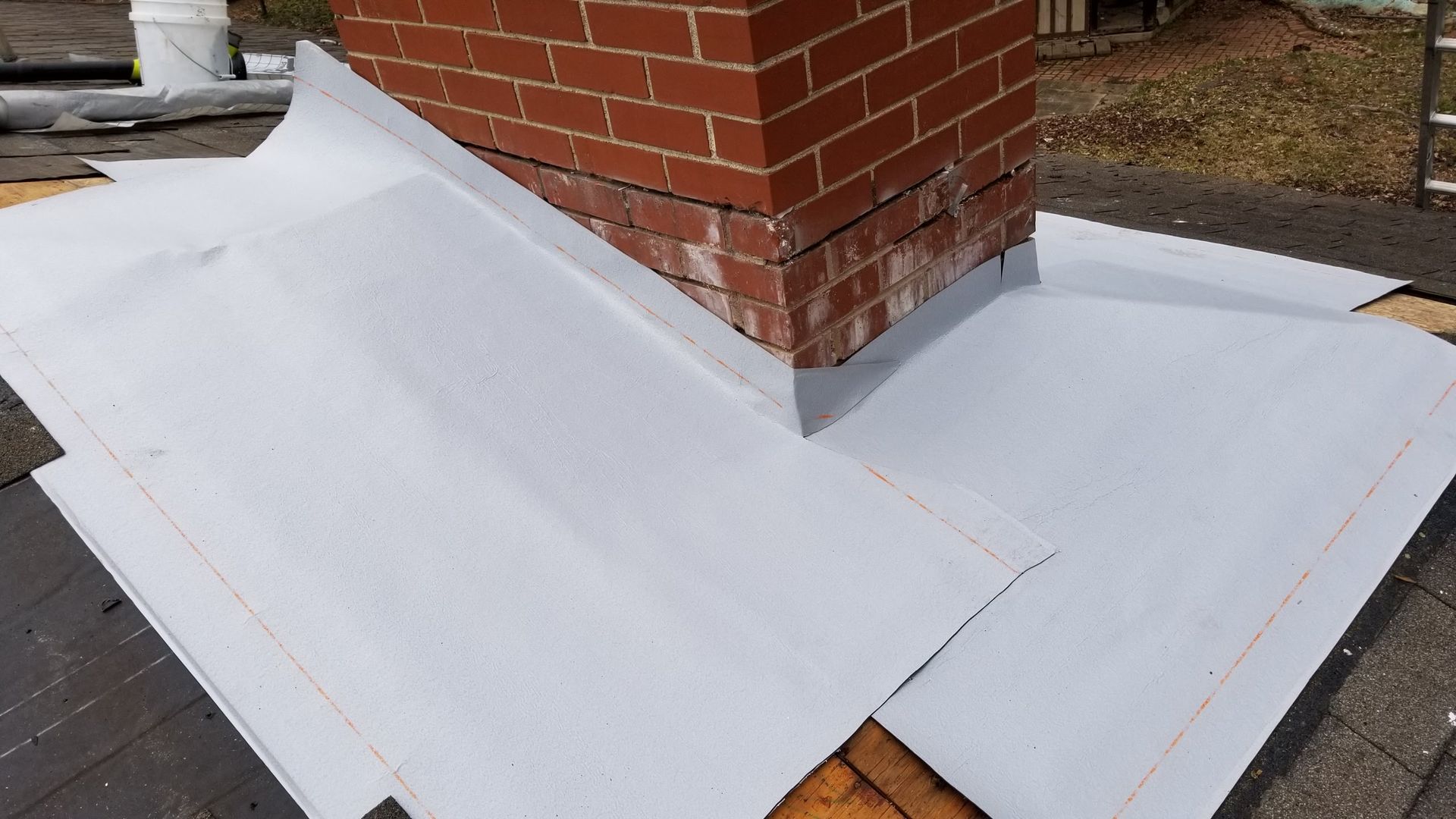 A brick chimney is sitting on top of a white roof.
