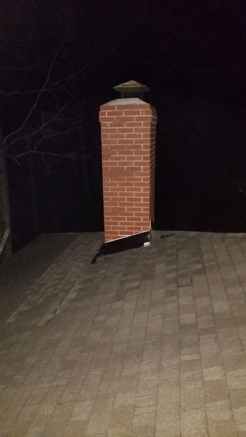 A brick chimney is sitting on top of a brick patio at night.