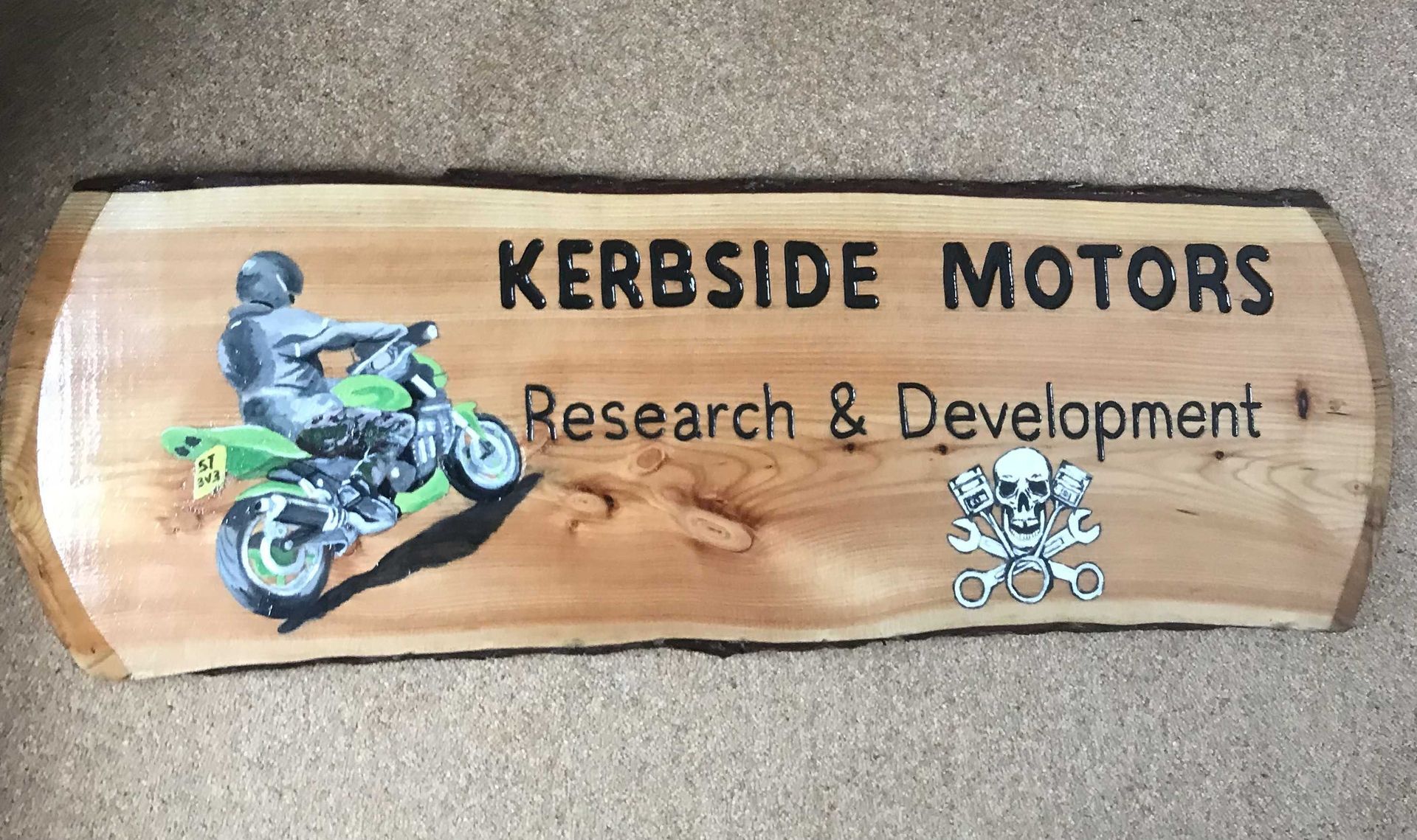 A wooden business sign for a mechanic with a full colour illustration of a motorbike.