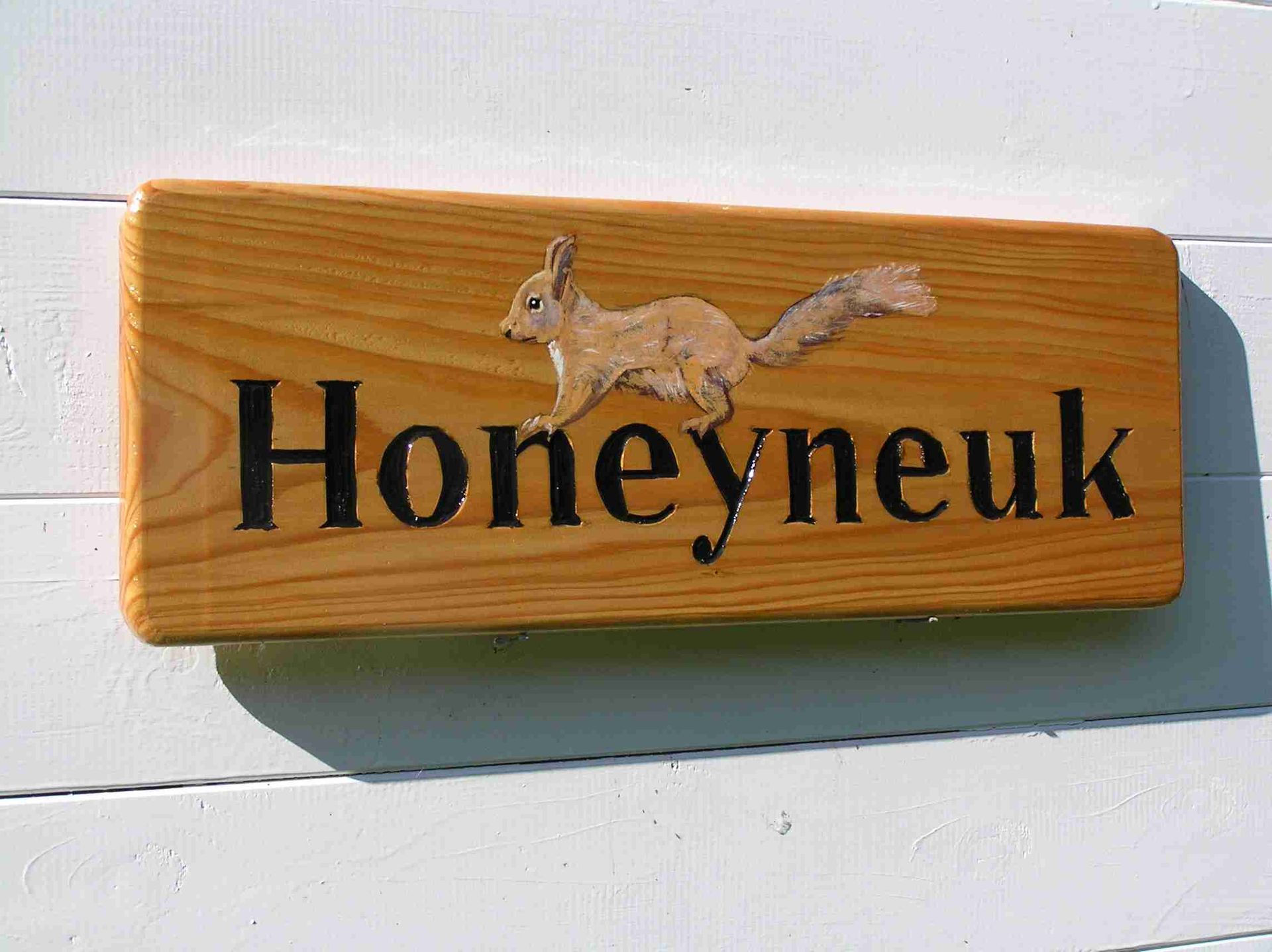 A wooden house sign with an animal picture