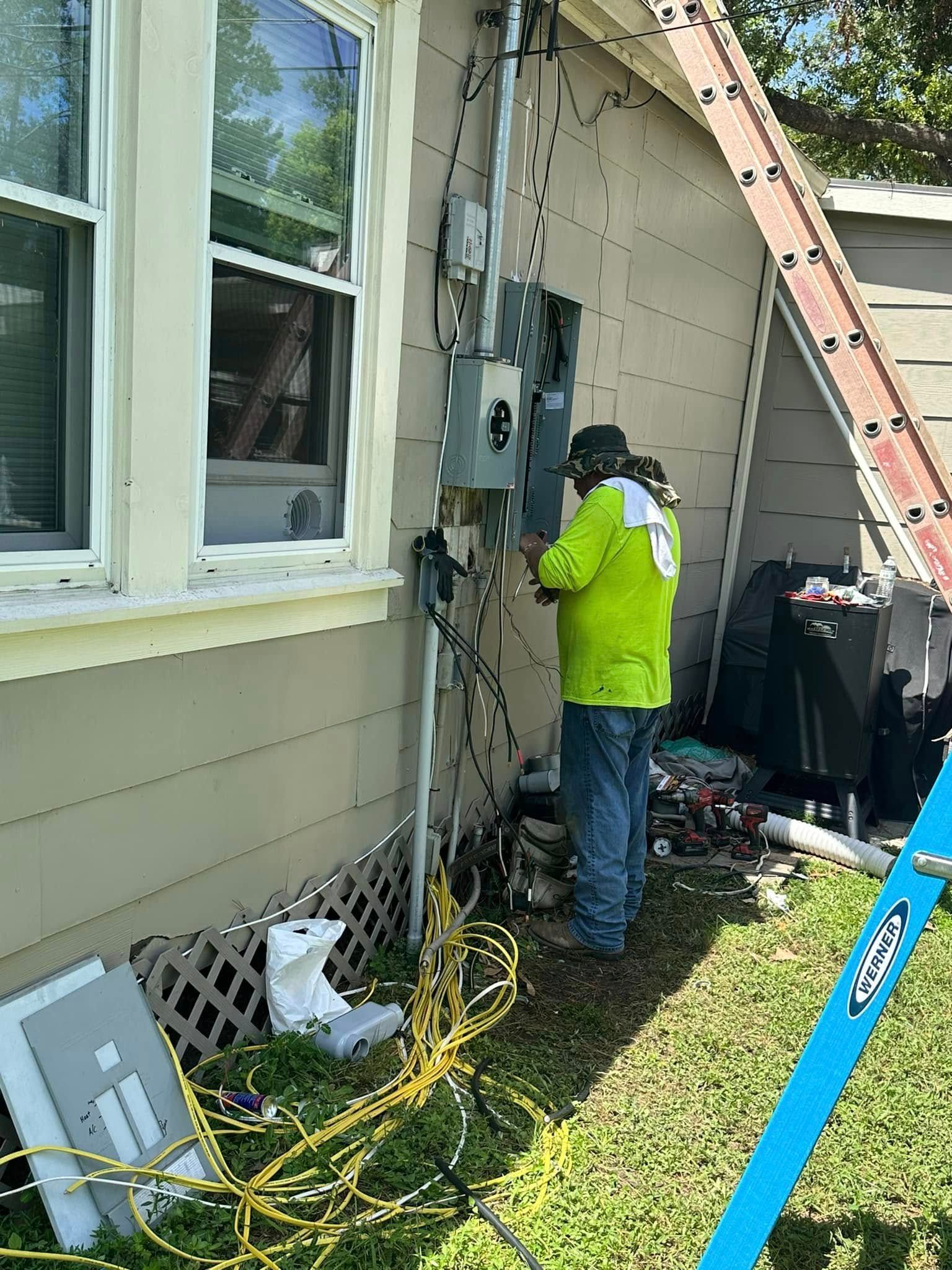 Technician in neon jacket inspecting electrical wiring outside a beige house