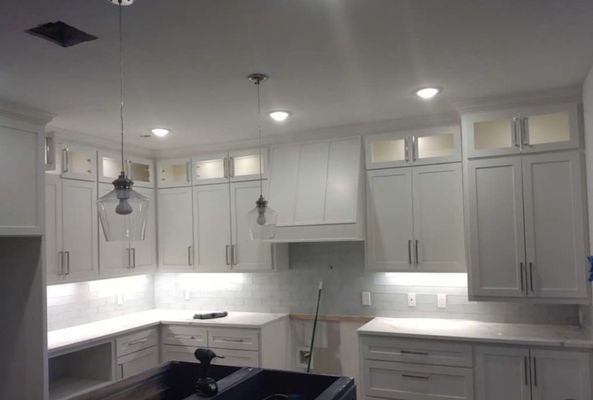 Bright white kitchen with cabinets, island, pendant lights, and under-cabinet lighting