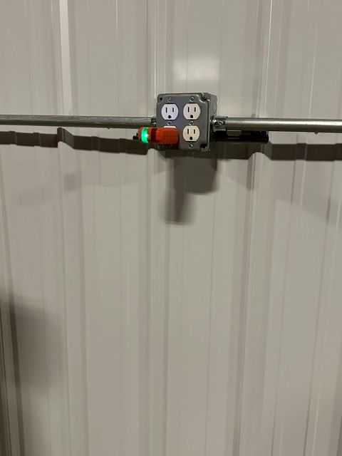 Outlet with a small plug-in device and glowing red and green lights on a wall panel