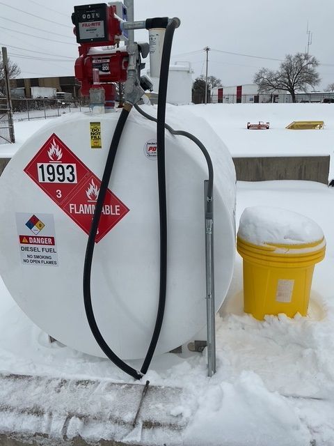 White fuel tank with red pump in snowy outdoor setting, labeled “1993” and “FLAMMABLE”