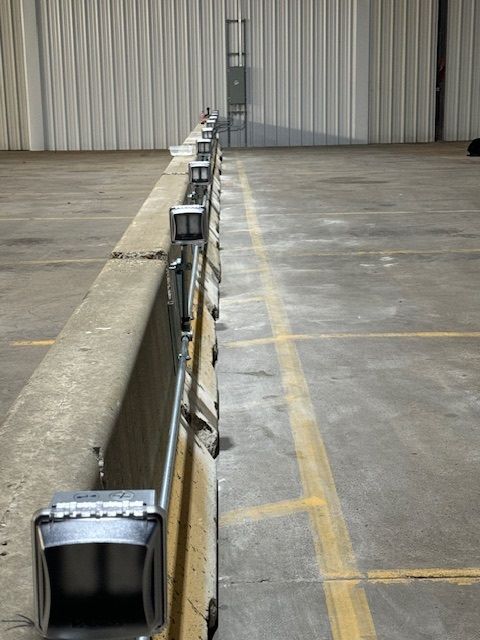 Long row of metal barriers in a warehouse loading area with a concrete floor and closed industrial door.