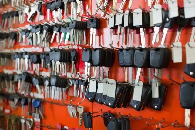 A wall filled with rows of keys, including car keys, displayed for sale on an orange background.