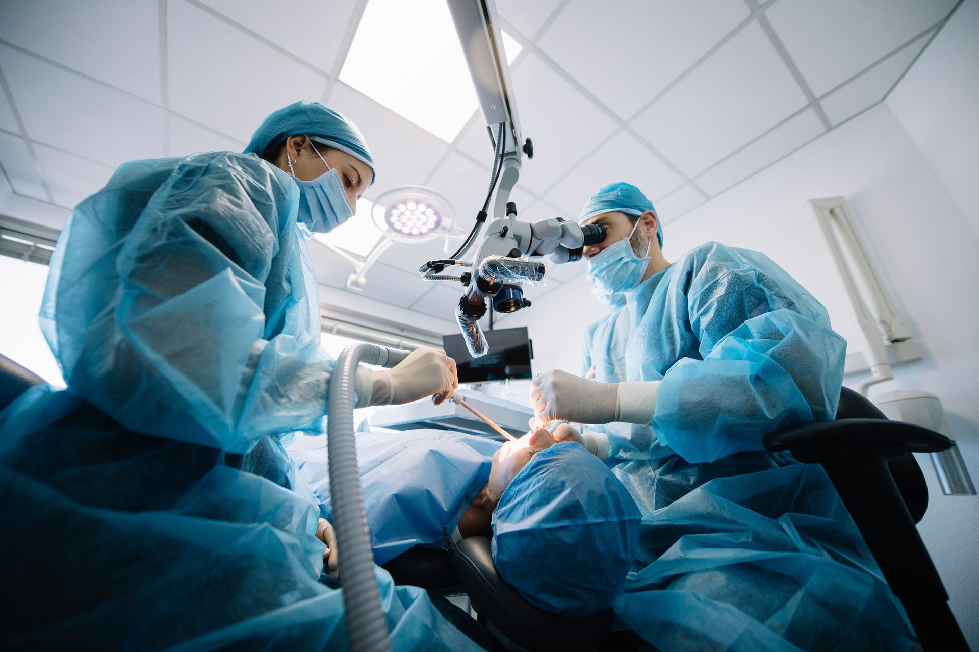 Dentist during a dental implant surgery with a patient. Dentist during a dental implant surgery with a patient.