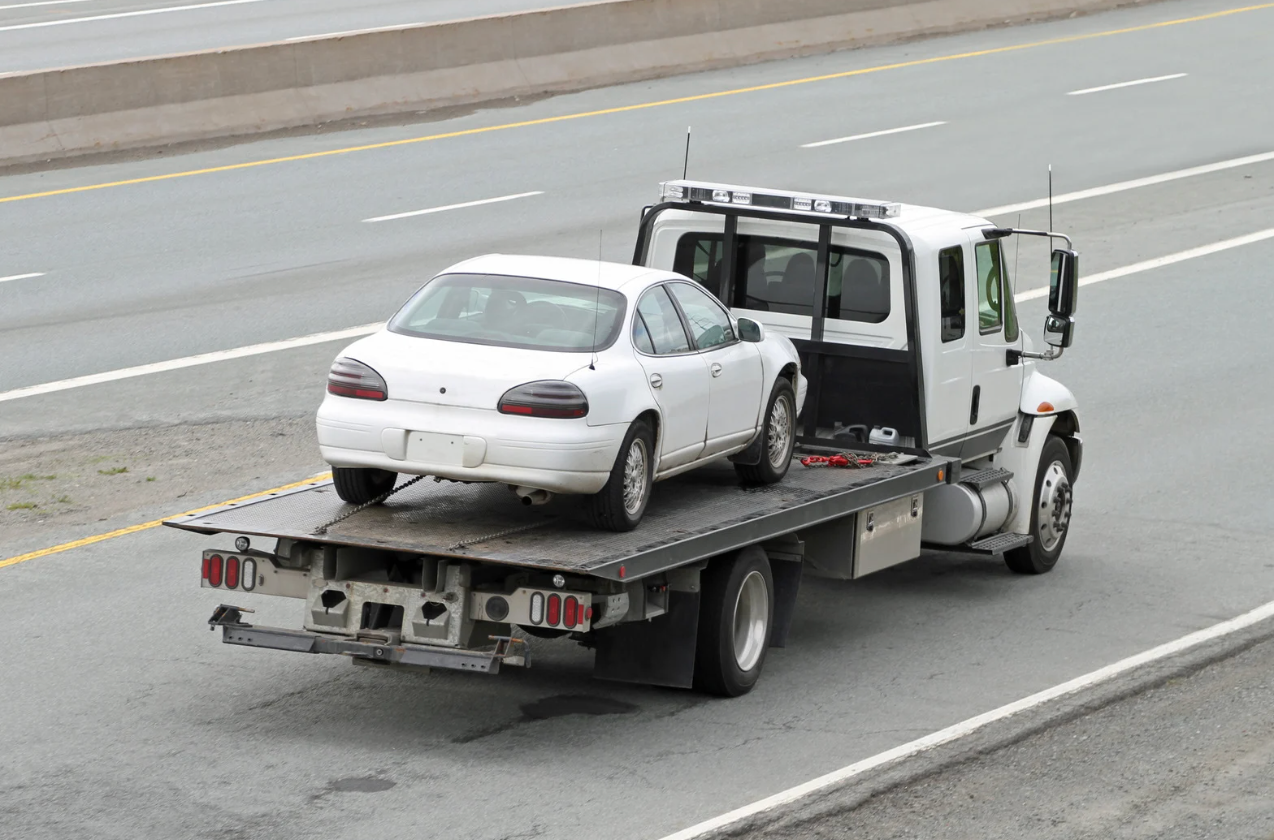 car being towed away on a flatbed tow truck down a highway